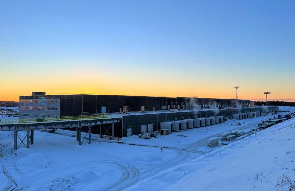 Kaldt vinterbilde av stort lager i solnedgang. Gule og blå fargetoner